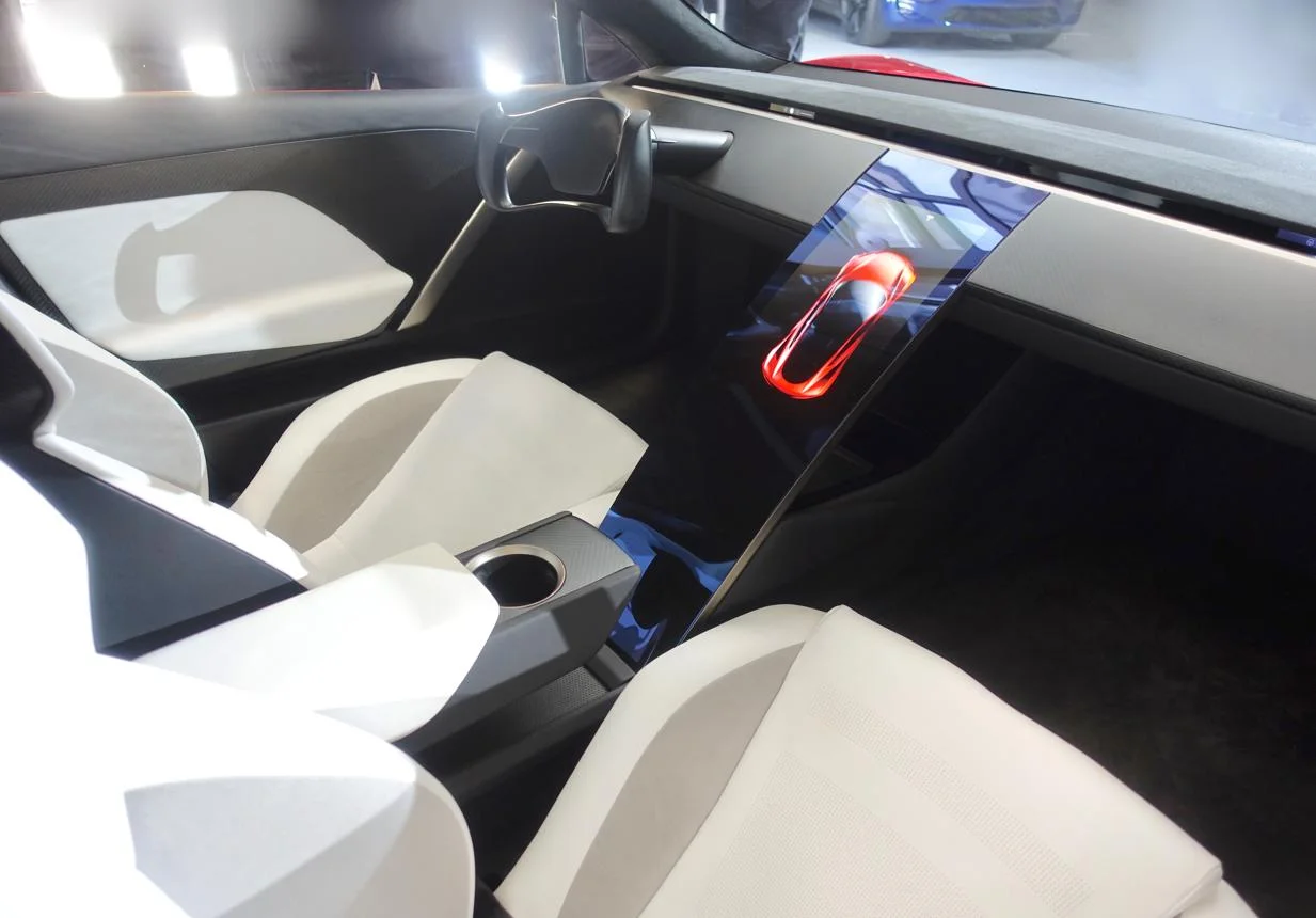 תא הנוסעים הלבן של Tesla Roadster עם הגה Yoke ומסך מרכזי