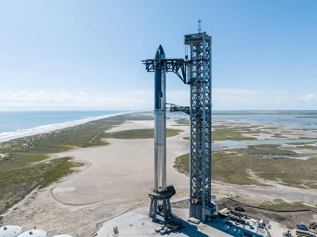 חללית Starship של SpaceX על כן השיגור לצד מגדל השיגור, בתצלום רשמי של החברה